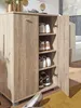 A wooden shoe cabinet with its door open, displaying several pairs of shoes on shelves. A pair of high heels is visible in the foreground. Náhled obrázku produktu