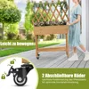 A woman is pushing a wooden planter box with a trellis on wheels. Produktbild-Vorschau