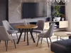 A modern living room with a round dining table and chairs in the foreground, a television and entertainment unit in the background. Produktbild-Vorschau
