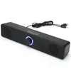 A black computer soundbar with a blue LED ring around the volume knob, placed on a white background. Voir les images du produit