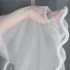 A hand is holding a sheer white curtain with a decorative wavy edge. Produktbild-Vorschau