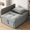A grey sofa bed with a pillow on it, placed on a wooden floor next to a wall. Produktbild-Vorschau