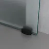 A close-up view of the bottom corner of a glass sliding door with a black handle attached to the glass. Produktbild-Vorschau