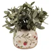A small potted plant with green leaves sits in a decorative ceramic pot with a strawberry pattern. Podgląd zdjęcia produktu