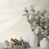 A close-up of a wall with a wavy pattern, with two white vases containing green eucalyptus branches and a telephone on a table in the foreground. Produktbild-Vorschau