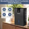 A black dehumidifier is placed on a wooden table next to a window with plants. Náhled obrázku produktu