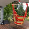A colorful hammock chair hanging on a wooden deck outdoors, surrounded by greenery. Náhled obrázku produktu
