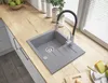 A modern kitchen sink with a granite finish, featuring a flexible faucet, set on a wooden countertop next to a window. Podgląd zdjęcia produktu