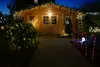 A wooden cabin decorated with Christmas lights, candy canes, and a small tree. Produktbild-Vorschau