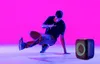 A person breakdancing next to a portable speaker. Produktbild-Vorschau