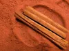 Close-up view of cinnamon sticks on a bed of cinnamon powder. Podgląd zdjęcia produktu