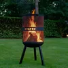 A BonFeu fire pit with a fire burning inside, set up on a green lawn in a garden setting. Produktbild-Vorschau