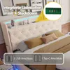 A bed with a tufted headboard and integrated lighting, featuring charging ports and decorative items on the shelf. Produktbild-Vorschau