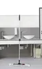 A mop is standing upright in a modern bathroom setting, in front of sinks and mirrors. Podgląd zdjęcia produktu