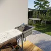 An outdoor sink area with a marble countertop, a sink, and a garden setting with a table and chairs. Náhľad obrázku produktu