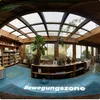 A panoramic view of a room with bookshelves, plants, and furniture, featuring a skylight ceiling. Produktbild-Vorschau