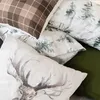 A close-up view of several pillows with different winter-themed patterns, including a plaid pattern, a forest scene, and a deer illustration. Produktbild-Vorschau