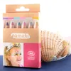 A box of face paint crayons for children, with a picture of a child with face paint on the front, and seashells in the background. Voir les images du produit