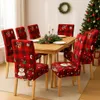 A dining table set with Christmas-themed chair covers, a centerpiece, and a Christmas tree in the background. Náhled obrázku produktu