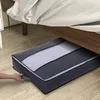 A person's hand is pulling a storage bag from under a bed. Produktbild-Vorschau