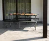 An outdoor patio with a picnic table and two benches set up for a meal. Podgląd zdjęcia produktu
