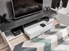 A modern TV stand with open and closed compartments and a pull-out drawer, with a TV on top and decorative items. Produktbild-Vorschau
