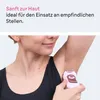 A woman is using a pink electric shaver on her underarm. Náhled obrázku produktu