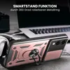 A close-up of a rose gold phone case with a ring stand, placed on a table next to headphones and a laptop. Produktbild-Vorschau