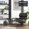 A fan is placed on the floor in a modern living room setting, next to a bookshelf and a chair. Náhled obrázku produktu