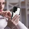 A woman is holding and looking at a smartphone with a black protective case. Produktbild-Vorschau