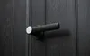 A close-up shot of a black door handle on a dark wooden door. Náhľad obrázku produktu
