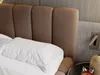 A close-up view of a bed with a brown upholstered headboard and white pillows. Produktbild-Vorschau