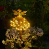 A solar-powered garden stake shaped like a fairy with lights, placed among flowers at night. Produktbild-Vorschau