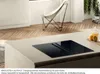 A modern kitchen island with an integrated induction cooktop and downdraft ventilation system, set in a bright, airy room with wooden floors and a butterfly chair. Podgląd zdjęcia produktu