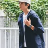 A man wearing a watch and jacket walks outdoors. Produktbild-Vorschau