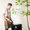 A man wearing a brown apron is smoking food on a grill. Produktbild-Vorschau