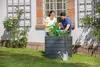 A couple is gardening in a raised planter box in front of a house. Anteprima dell’immagine prodotto