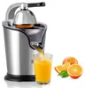 A stainless steel electric citrus juicer is shown in operation, with orange juice being poured into a glass. Sliced oranges and leaves are placed next to the juicer. Náhled obrázku produktu