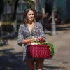 A woman is walking outdoors carrying a basket of fresh vegetables. Náhled obrázku produktu