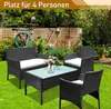 A rattan garden furniture set with a table and seating is arranged on a green lawn in a garden setting, with a wooden fence and lush greenery in the background. Anteprima dell’immagine prodotto