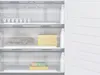 Interior view of an open refrigerator or freezer, showing shelves and drawers with some food items. Produktbild-Vorschau