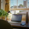 A desk with a laptop, lamp, and water bottle in front of a window with a view of buildings. Náhľad obrázku produktu