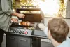 Two people are grilling outdoors on a sunny day. Produktbild-Vorschau