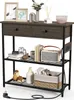 A console table with two drawers and two shelves, decorated with various items, including books, a radio, and decorative objects. A power cord is visible at the bottom. Anteprima dell’immagine prodotto