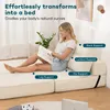 A woman sits on a cream-colored sofa bed, reading a magazine, with text overlays highlighting support features. Produktbild-Vorschau