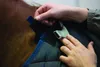 A close-up view of hands adjusting a horse blanket on a horse. Produktbild-Vorschau