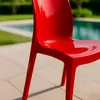A red chair is placed on a patio next to a swimming pool. Anteprima dell’immagine prodotto