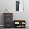 A chest of drawers and a shoe rack with shoes on it, against a grey wall. Voir les images du produit