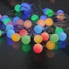 A close-up, slightly angled view of a string of colorful LED party lights on a dark, reflective surface. Produktbild-Vorschau