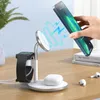 A hand is placing an iPhone onto a white 3-in-1 wireless charging stand that also holds an Apple Watch and AirPods. Podgląd zdjęcia produktu